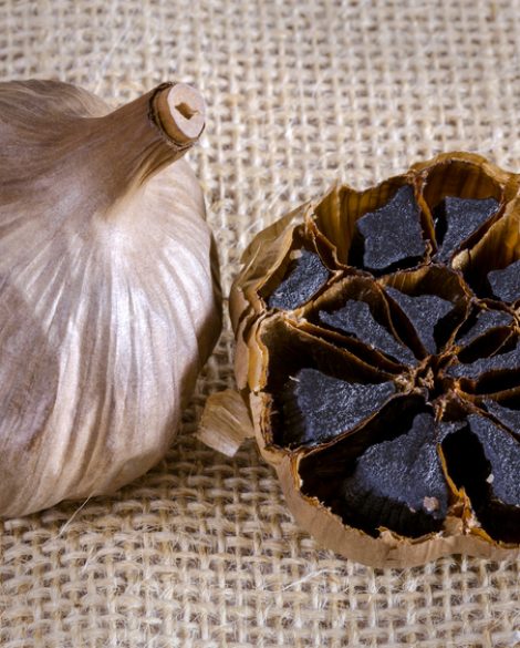 Black garlic bulb with cross section showing black cloves